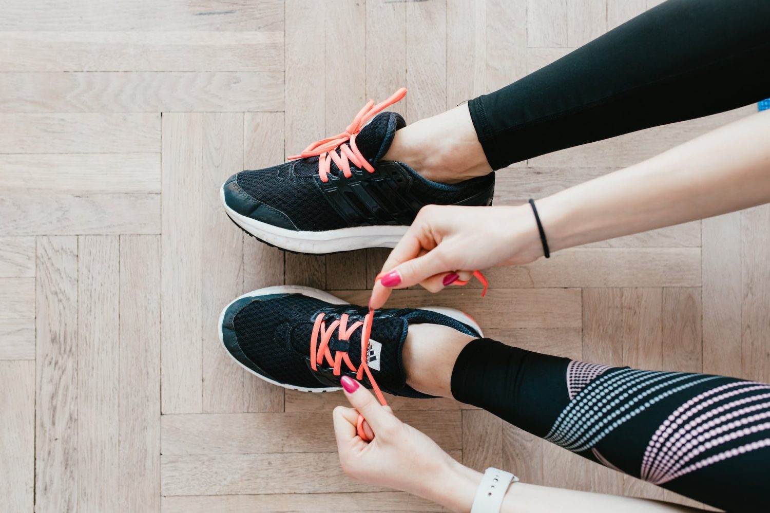 unrecognizable young sportswoman tying sneakers on floor