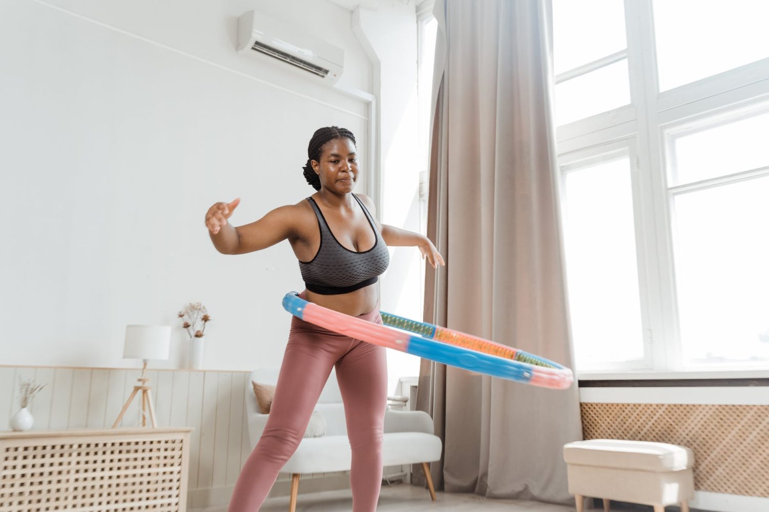 a woman in tank top using a hula hoop