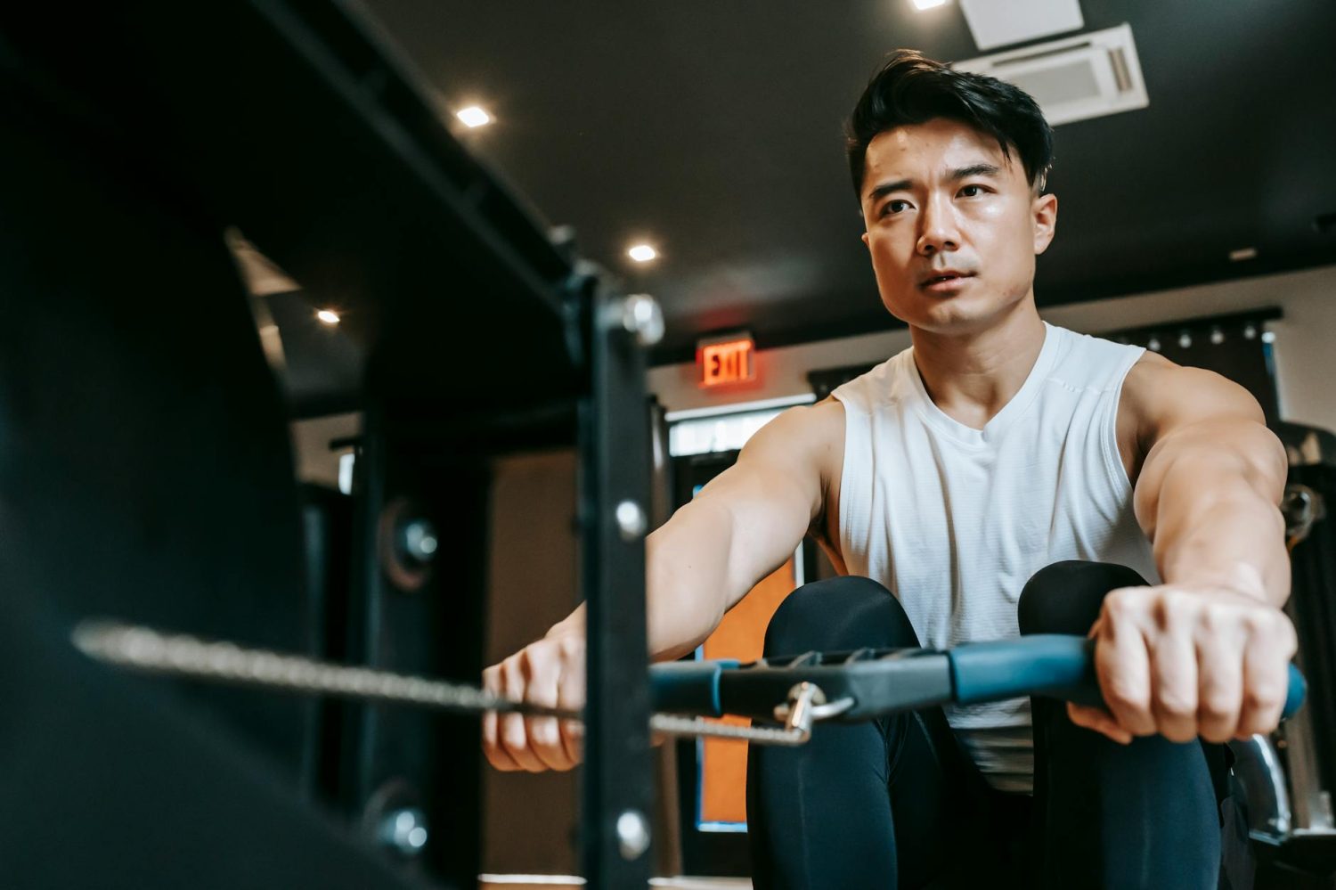 focused ethnic sportsman doing exercises on rowing machine